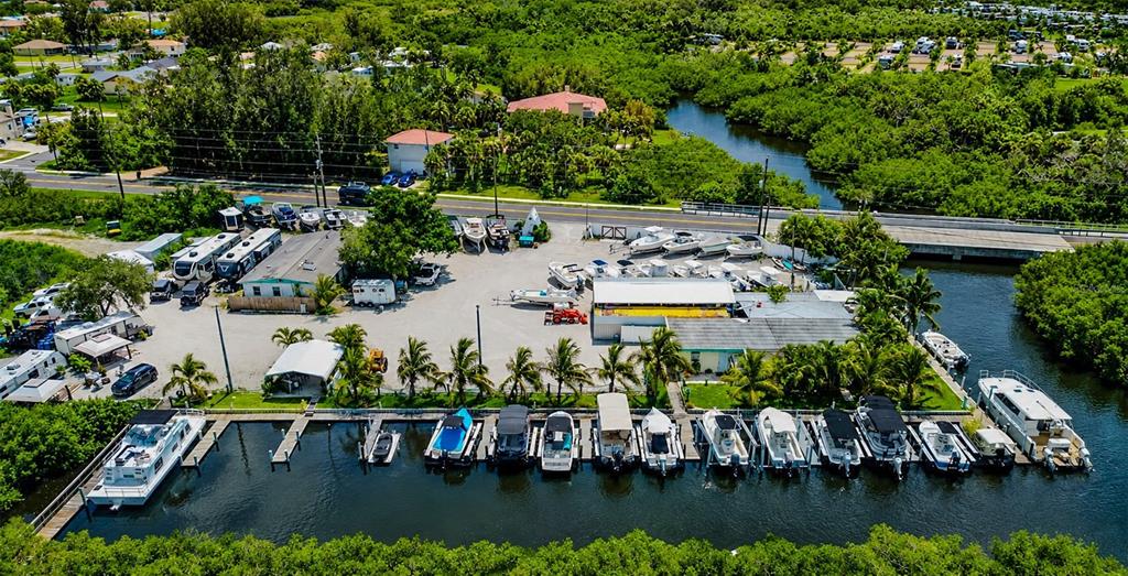 An aerial view shows a marina with numerous boats docked along a canal and parked trailers — 6817 BAYSHORE ROAD, PALMETTO, FL