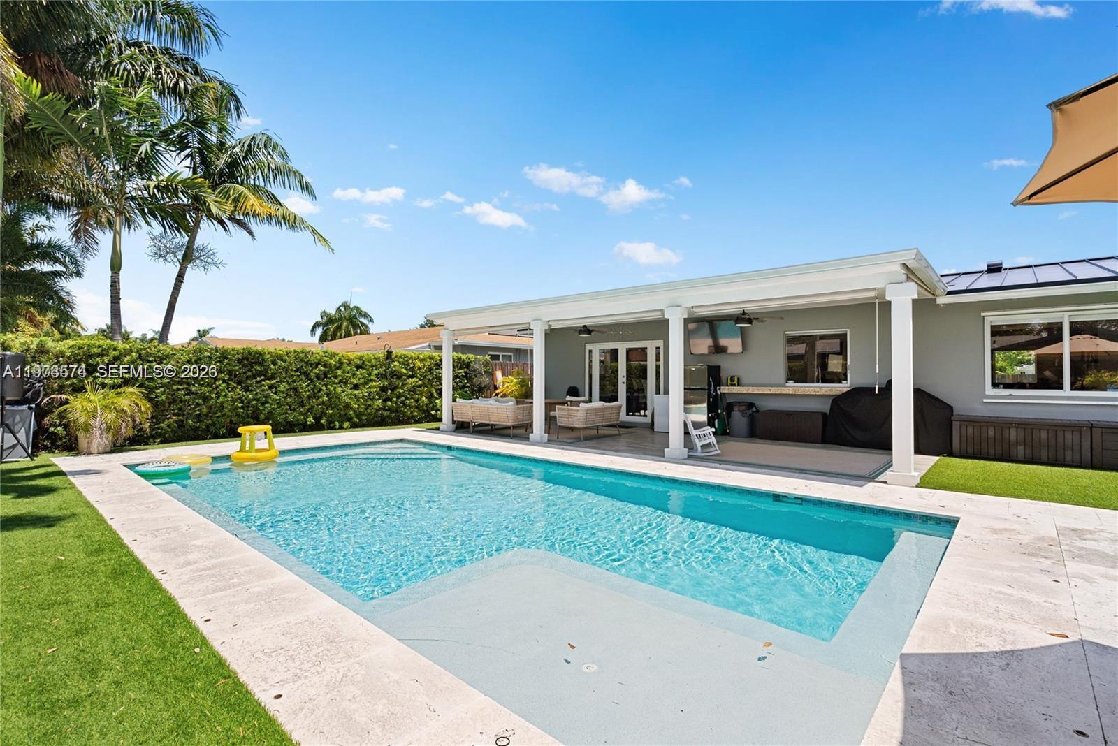 A rectangular swimming pool sits in a backyard with a covered patio and palm trees — 19900 SW 83rd Ave, Cutler Bay FL 33189, CUTLER BAY, FL