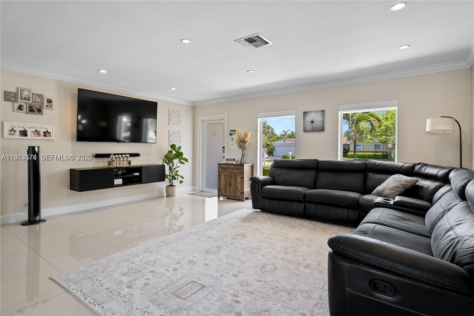 A living room features a large black sectional sofa, a wall-mounted television, and tile flooring — 19900 SW 83rd Ave, Cutler Bay FL 33189, CUTLER BAY, FL