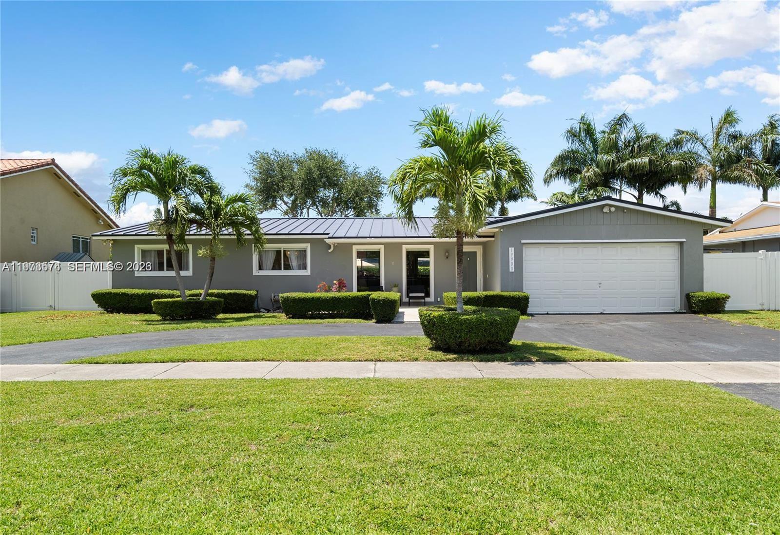 A single-story gray house features a metal roof, a two-car garage, and manicured landscaping — 19900 SW 83rd Ave, Cutler Bay FL 33189, CUTLER BAY, FL