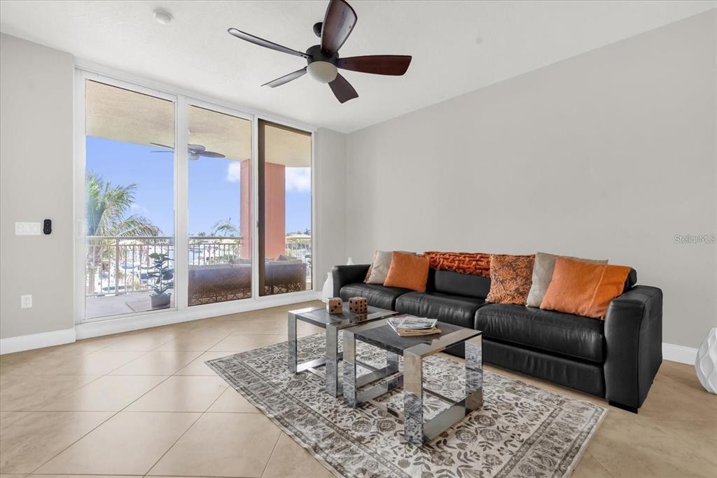 A living room features a black leather sofa, two glass coffee tables, and a balcony view — 606 RIVIERA DUNES WAY UNIT 207, PALMETTO, FL