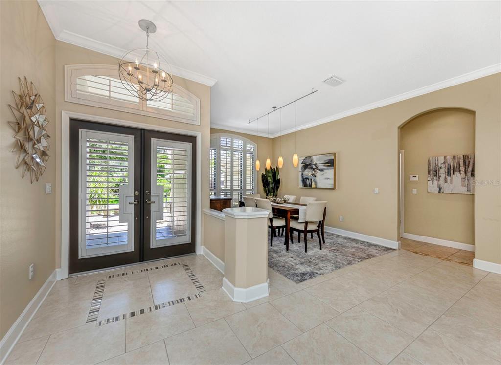 An entryway with tile floors leads to a dining area featuring a chandelier and windows — 3675 JANUS WAY, PALM HARBOR, FL