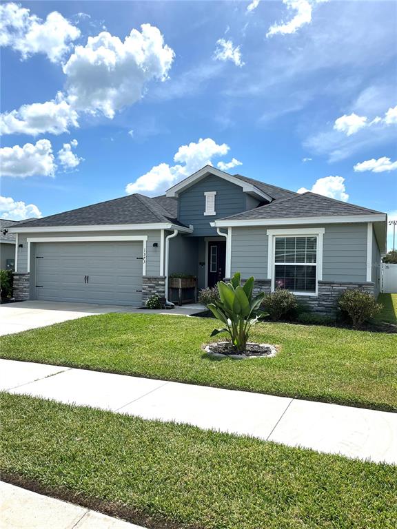 A single-story house with gray siding, a stone base, and a two-car garage — 1373 MEZZAVALLE WAY, AUBURNDALE, FL