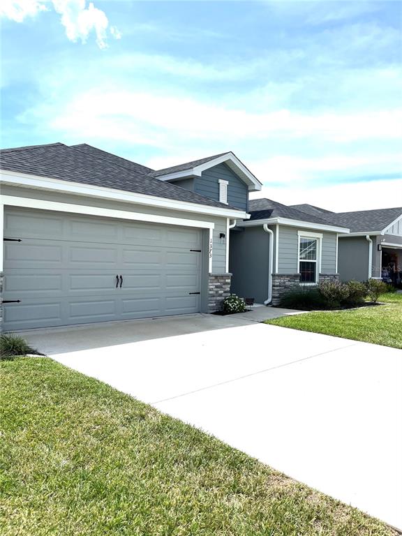 A single-story house with a gray garage, stone accents, and a concrete driveway — 1373 MEZZAVALLE WAY, AUBURNDALE, FL