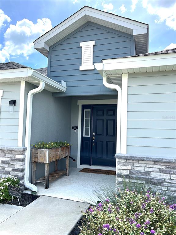 The exterior of a house features blue siding, a dark door, and a stone base — 1373 MEZZAVALLE WAY, AUBURNDALE, FL