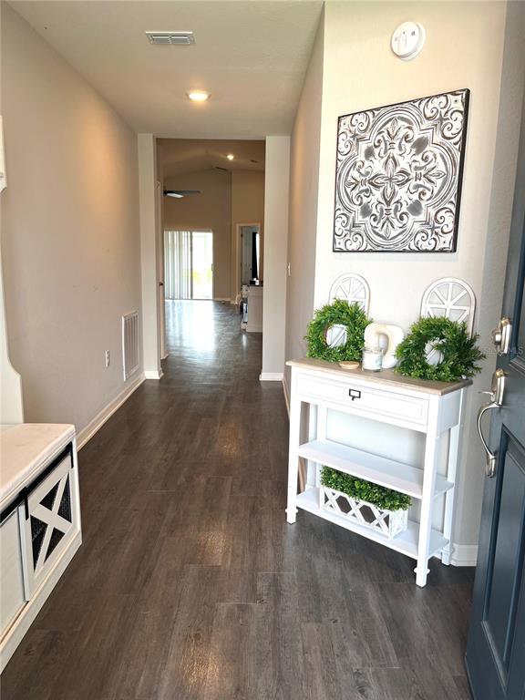 A long hallway with dark wood-look flooring leads toward an open living area — 1373 MEZZAVALLE WAY, AUBURNDALE, FL