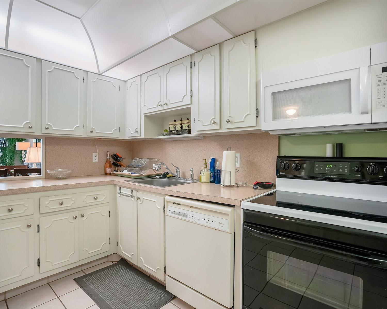 A kitchen with white cabinets, laminate countertops, a black oven, and a built-in microwave — 3090 N Course Drive # 112, Pompano Beach FL 33069, POMPANO BEACH, FL