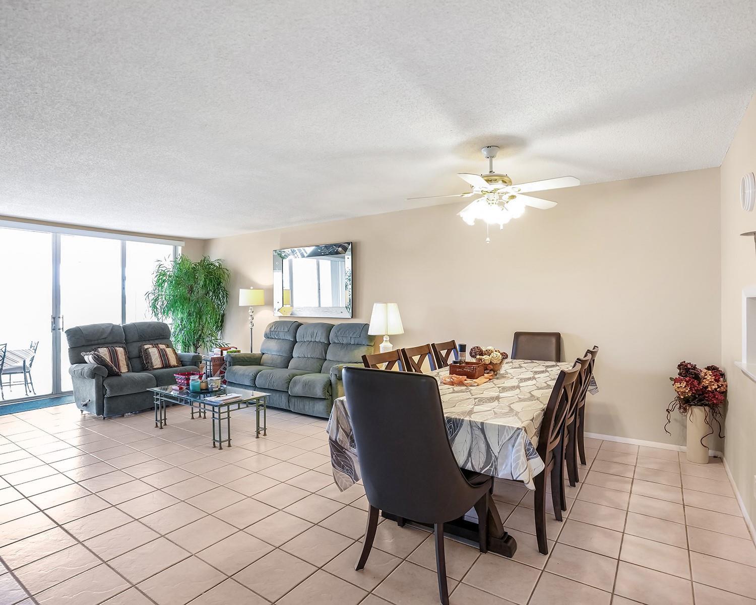 An open-concept living and dining area features tiled floors, a ceiling fan, and sliding doors — 3090 N Course Drive # 112, Pompano Beach FL 33069, POMPANO BEACH, FL
