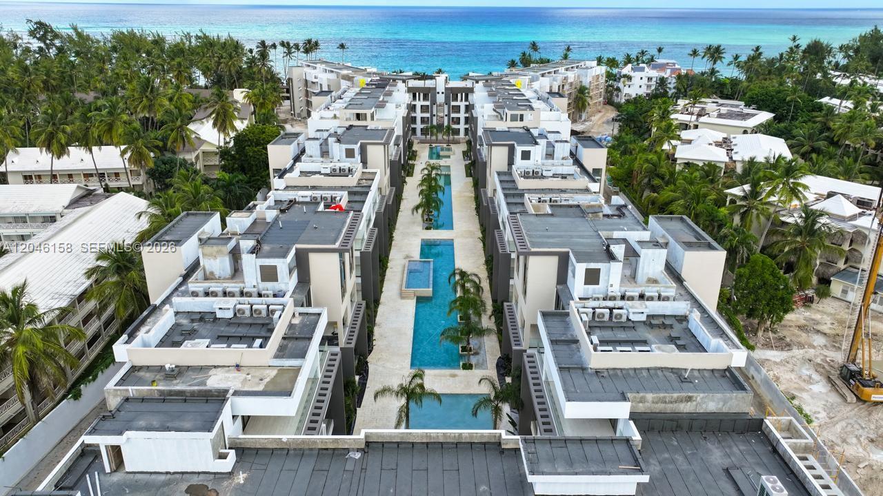 An aerial view shows a modern apartment complex with a central swimming pool and palm trees — 0 E Avenida Alemania Esq. El Dorado # 3, FL, FL