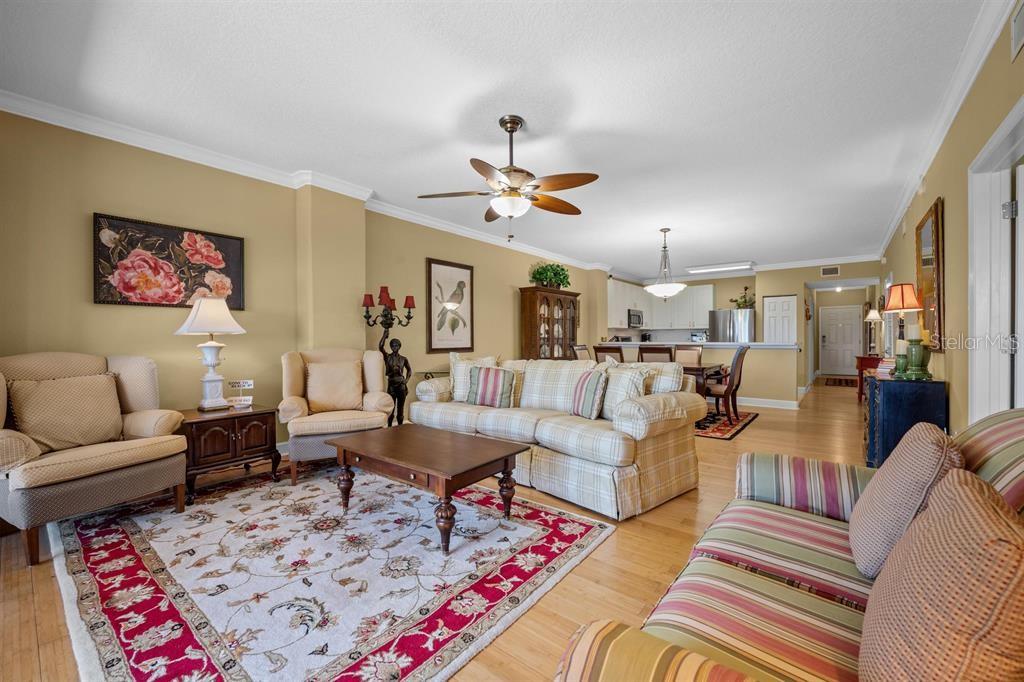A living room features a plaid sofa, patterned area rug, and hardwood flooring — 80 SURFVIEW DRIVE UNIT 118, PALM COAST, FL