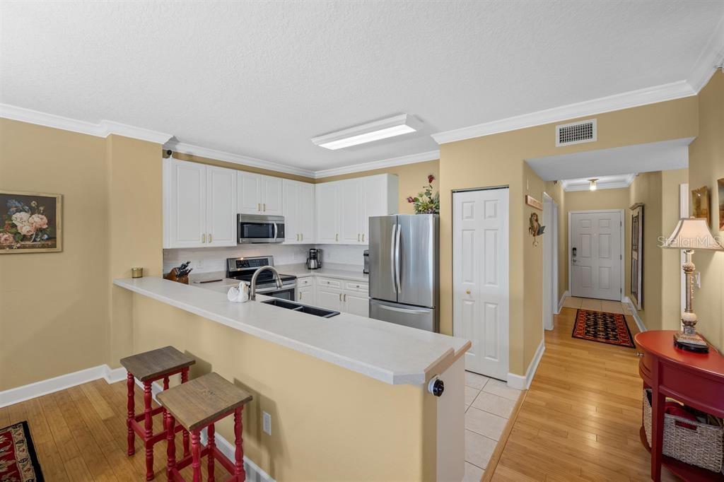 A kitchen with white cabinets, stainless steel appliances, and a breakfast bar with two stools — 80 SURFVIEW DRIVE UNIT 118, PALM COAST, FL