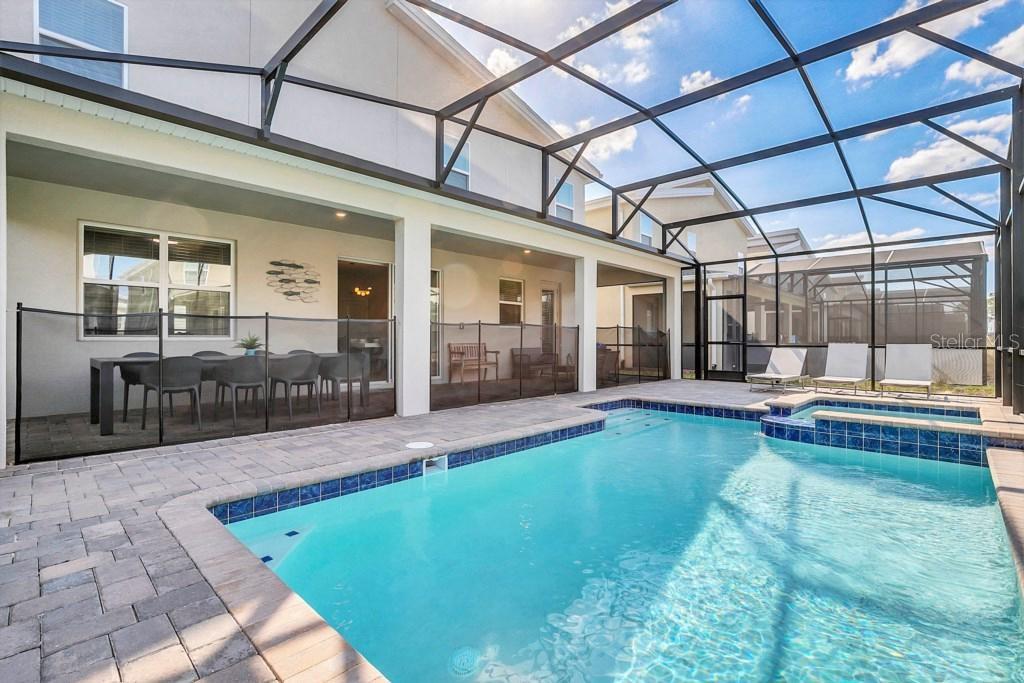 A swimming pool and spa sit on a paved patio enclosed by a screened lanai — 4541 TARGET BOULEVARD, KISSIMMEE, FL