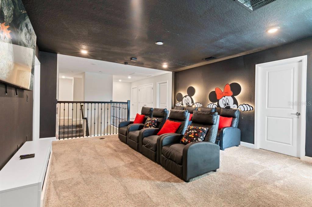 A home theater room features black walls, Mickey and Minnie Mouse wall art, and theater seating — 4541 TARGET BOULEVARD, KISSIMMEE, FL