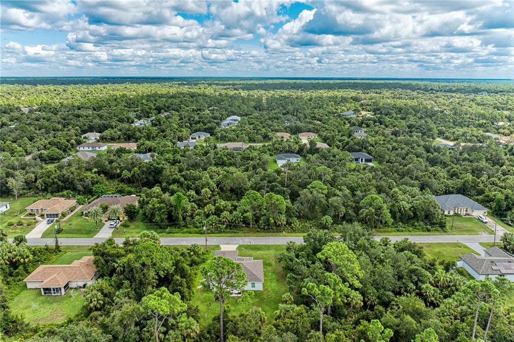 An aerial view shows several single-family homes surrounded by dense forest under a cloudy sky — Lot 25 BILLINGHAM LANE, NORTH PORT, FL