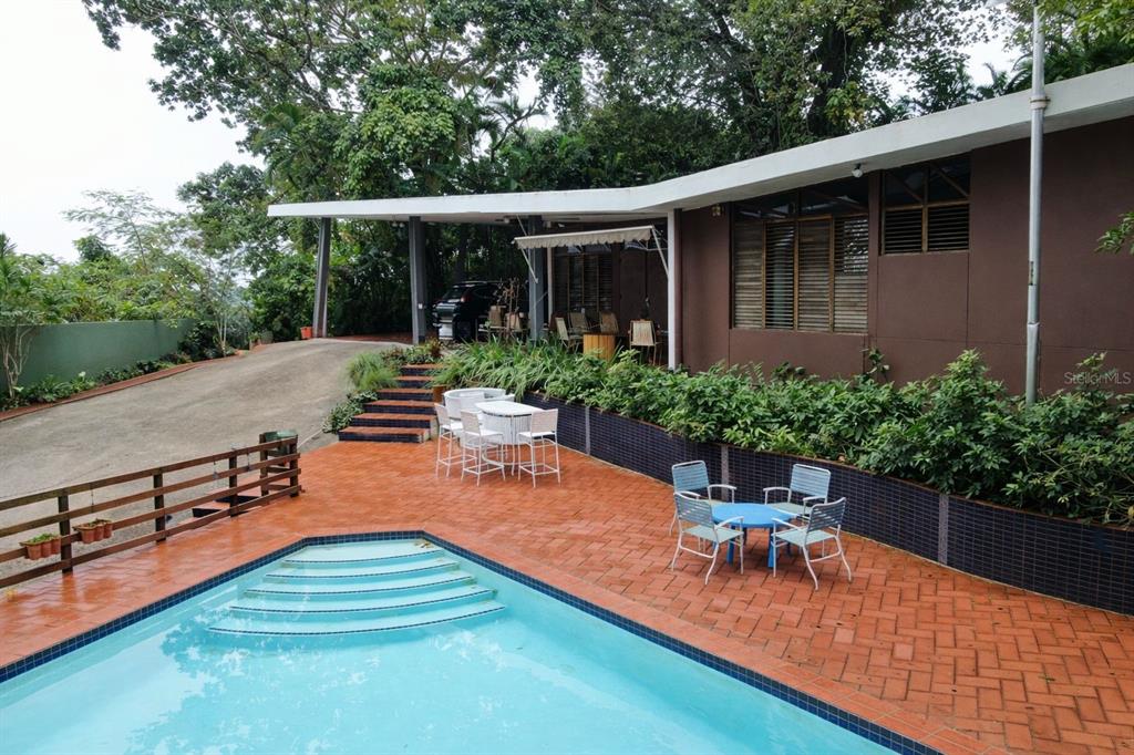 An outdoor patio with a swimming pool, dining sets, and a house with brown siding — Beverly Hills 1, SAN JUAN, PR