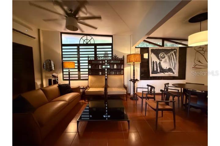 A living and dining area with a leather sofa, tile floors, and large windows — Beverly Hills 1, SAN JUAN, PR