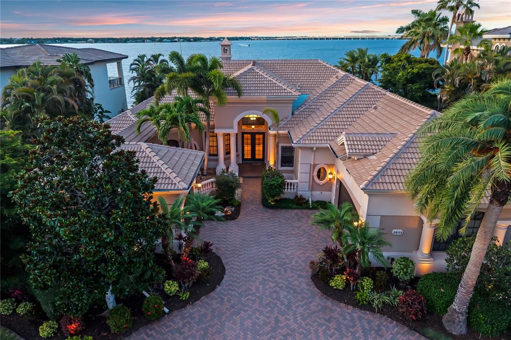 An aerial view of a waterfront house with a paved circular driveway and tile roof — 3803 HAWK ISLAND DRIVE, BRADENTON, FL