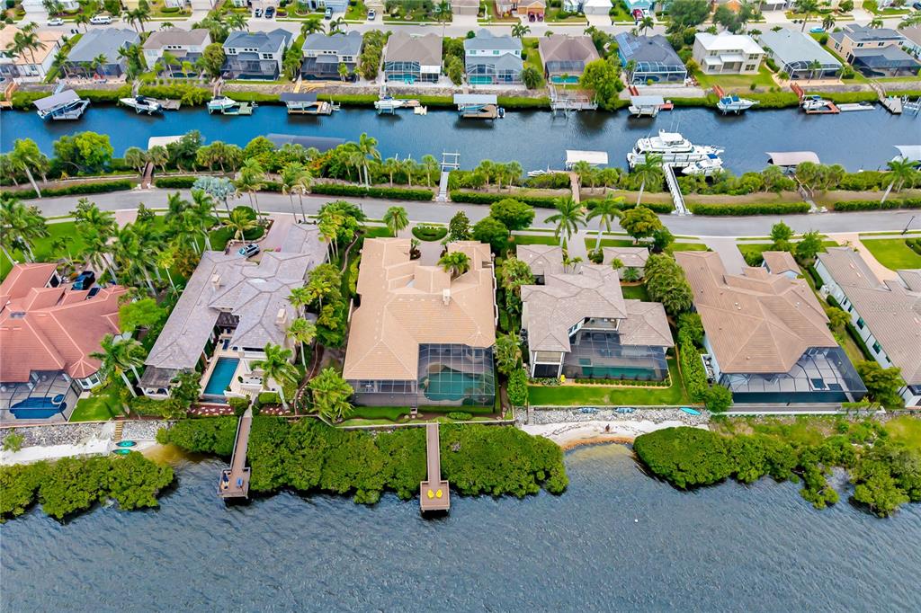 An aerial view shows several waterfront homes with swimming pools and private docks along a canal — 3803 HAWK ISLAND DRIVE, BRADENTON, FL