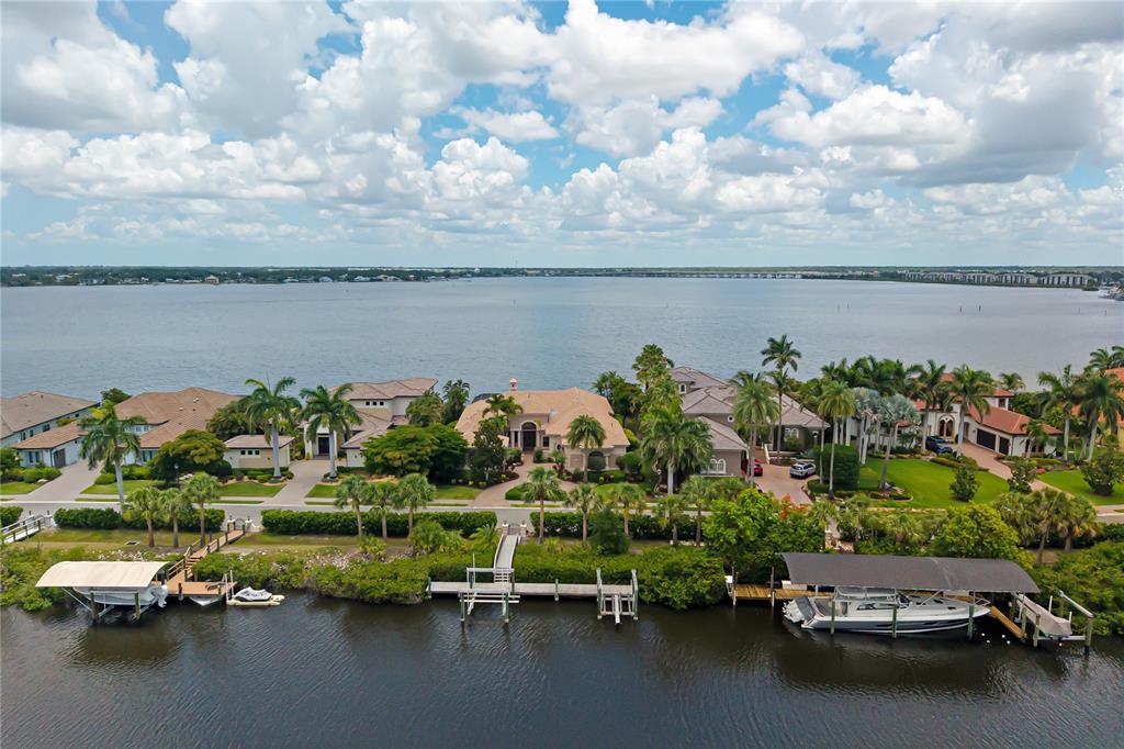 An aerial view shows waterfront homes with private boat docks along a canal at sunset — 3803 HAWK ISLAND DRIVE, BRADENTON, FL