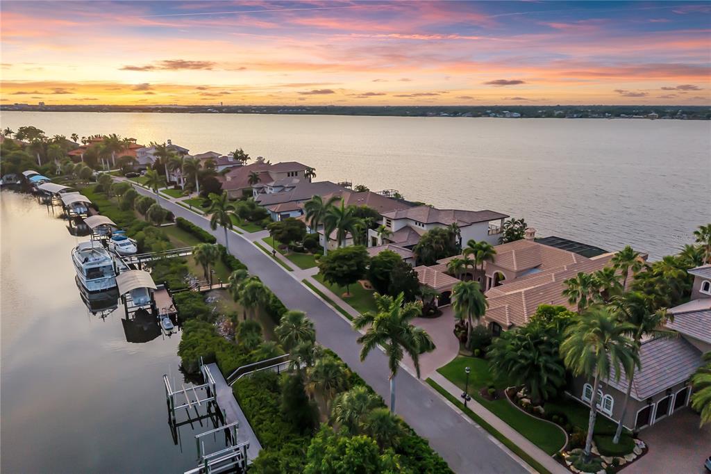 An aerial view shows several waterfront homes with swimming pools and private docks at dusk — 3803 HAWK ISLAND DRIVE, BRADENTON, FL