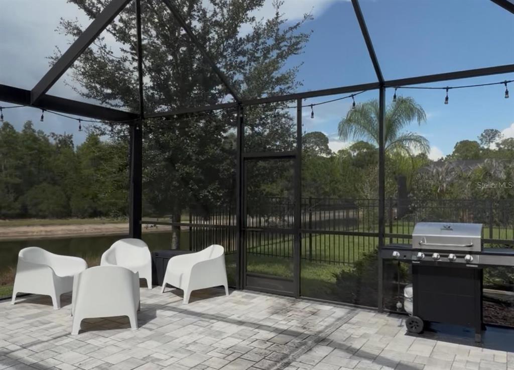 A screened-in patio features white chairs, a grill, and a view of a pond — 18071 AERO AVENUE, LAND O LAKES, FL