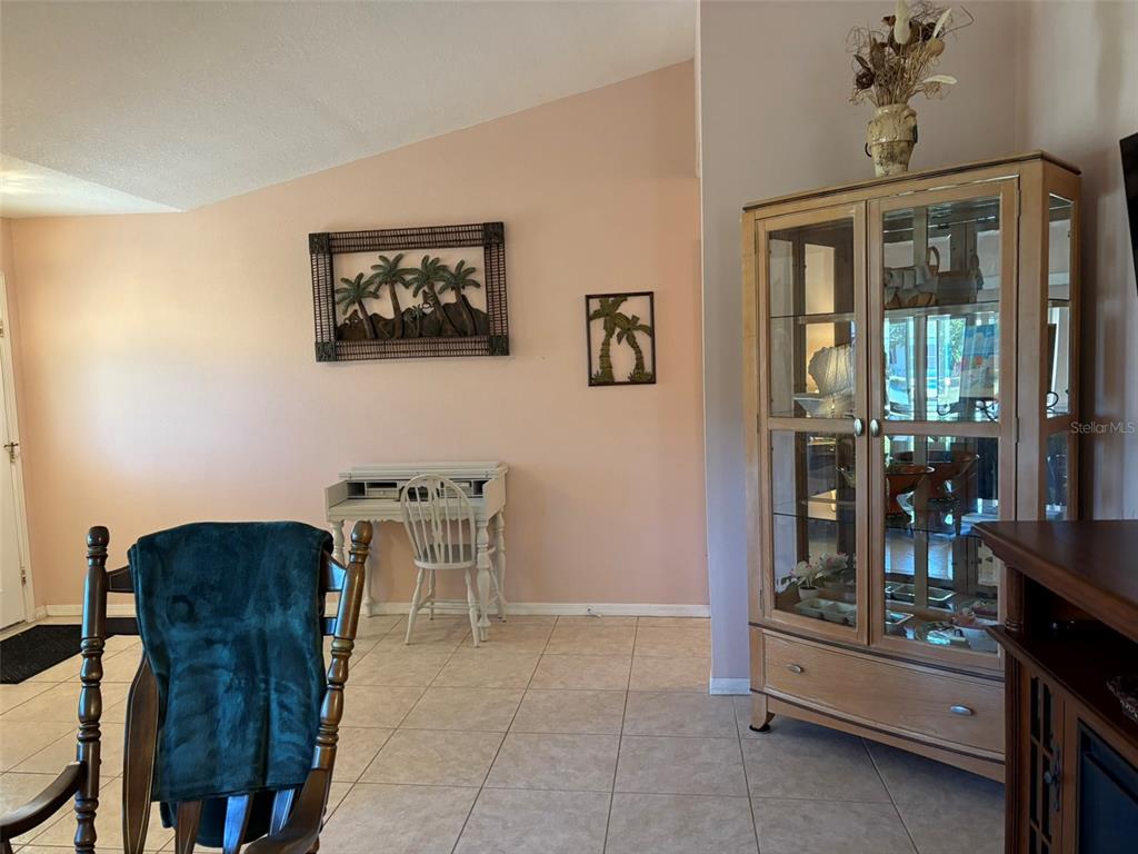 A room with tile flooring, a white desk, and a wooden display cabinet against walls — 17377 LAKE WORTH BOULEVARD, PORT CHARLOTTE, FL