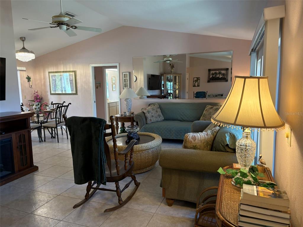 A living room with tile floors, a large mirror, a sofa, and a rocking chair — 17377 LAKE WORTH BOULEVARD, PORT CHARLOTTE, FL