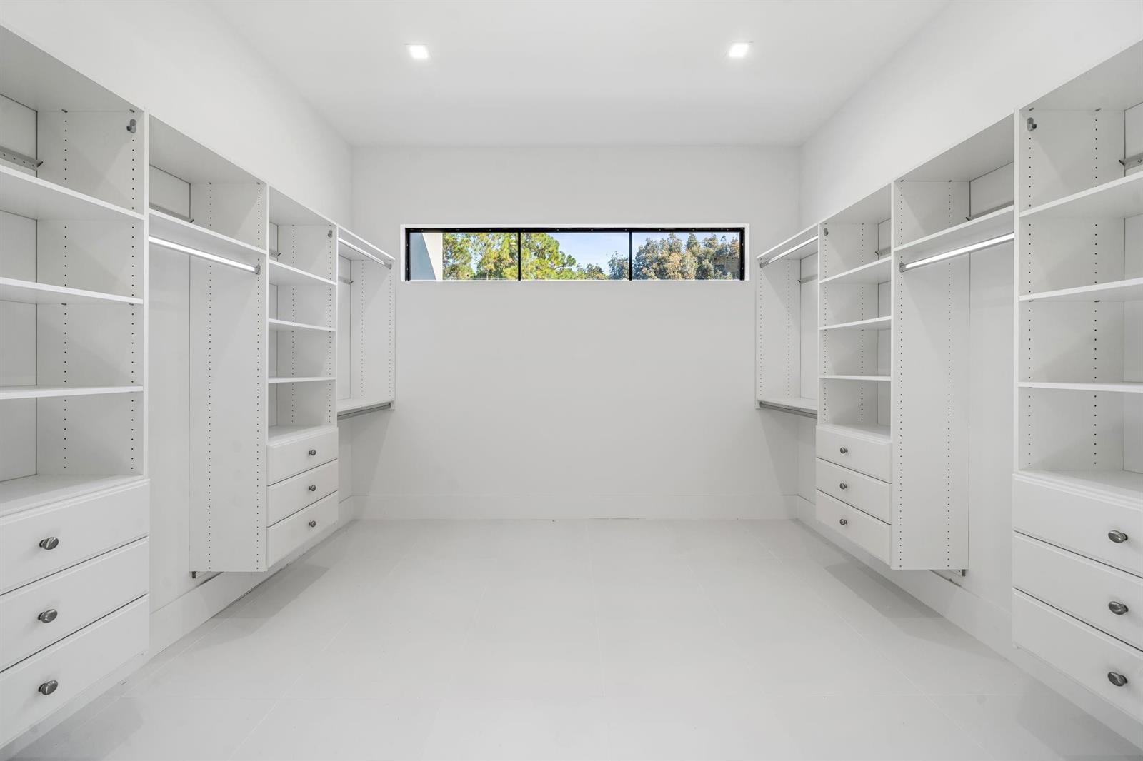 A walk-in closet features white custom shelving, drawers, and a horizontal window on the back wall — 18651 49th Street, Loxahatchee FL 33470, LOXAHATCHEE, FL