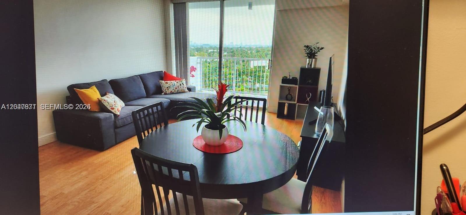 A living and dining area features a dark sofa, round table, and balcony access — 2000 NE 135th St # 806, North Miami FL 33181, NORTH MIAMI, FL
