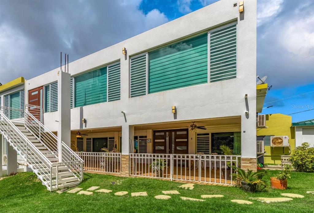 A two-story white house with an exterior staircase, large windows, and a ground-level patio — Calle 2 CARRETERA OESTE 169 UNIT 169, LUQUILLO, PR