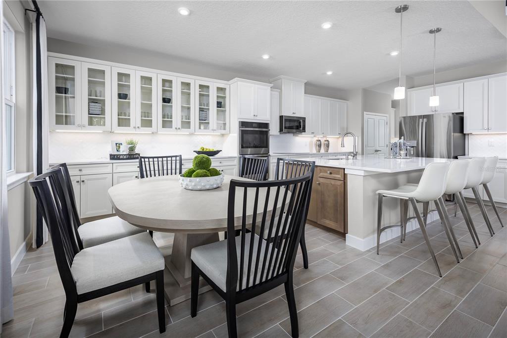 A kitchen with white cabinets, a center island, and a round dining table with chairs — 117 VENETIAN PALMS BOULEVARD, NEW SMYRNA BEACH, FL