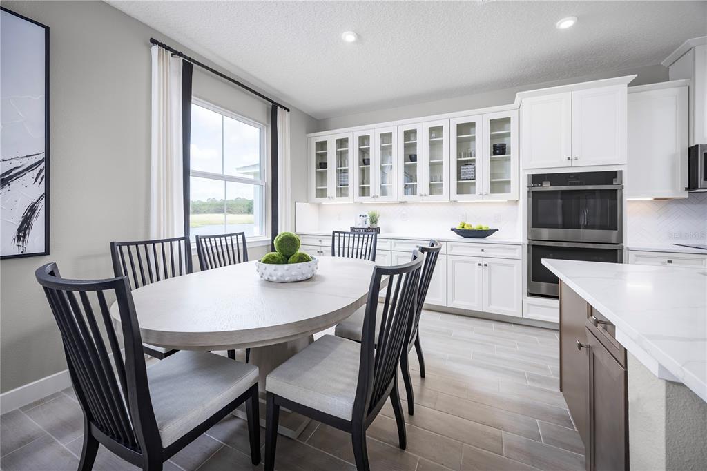 A dining area features a light wood oval table, black chairs, and white cabinetry — 117 VENETIAN PALMS BOULEVARD, NEW SMYRNA BEACH, FL