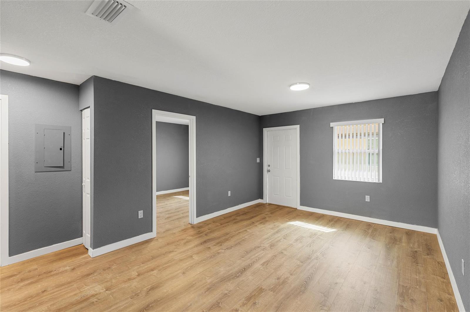 A room with gray walls, wood-look flooring, a white door, and a window with blinds — 233 NW 12th Court, Pompano Beach FL 33060, POMPANO BEACH, FL
