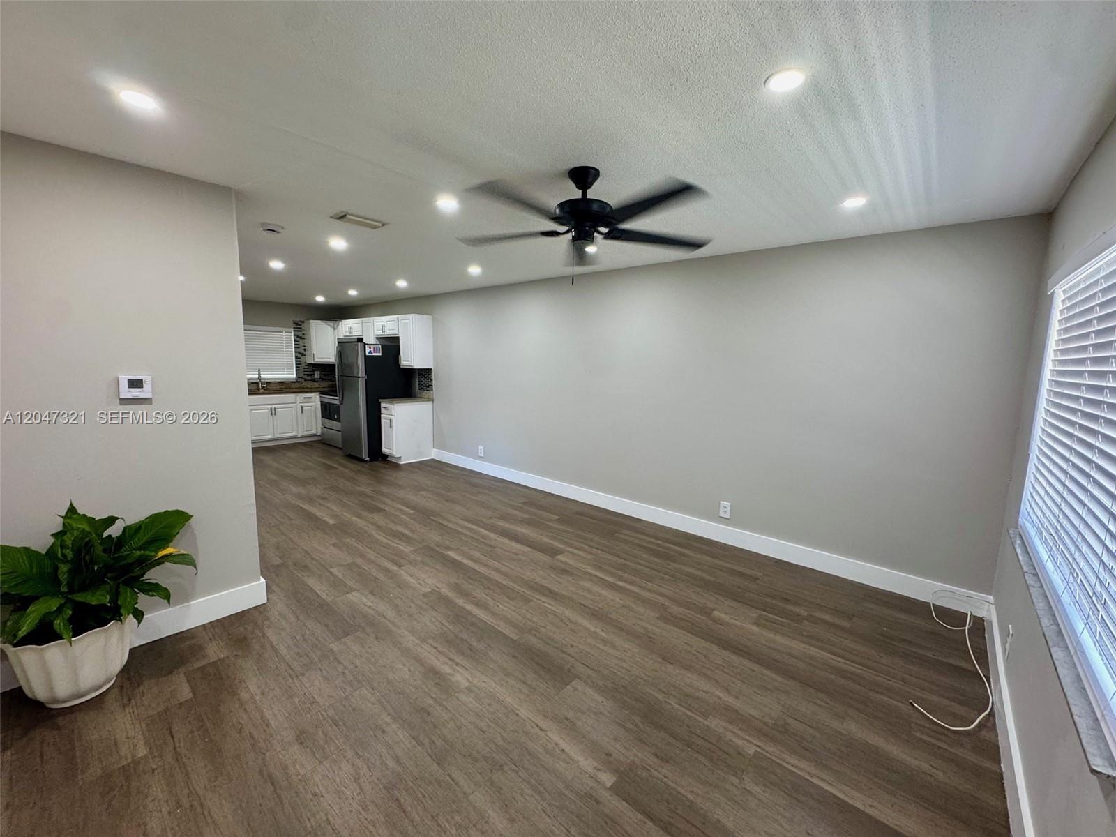 An open-concept living area features wood-look flooring, a ceiling fan, and an adjacent kitchen — 5410 NW 16th St # 1, Lauderhill FL 33313, LAUDERHILL, FL