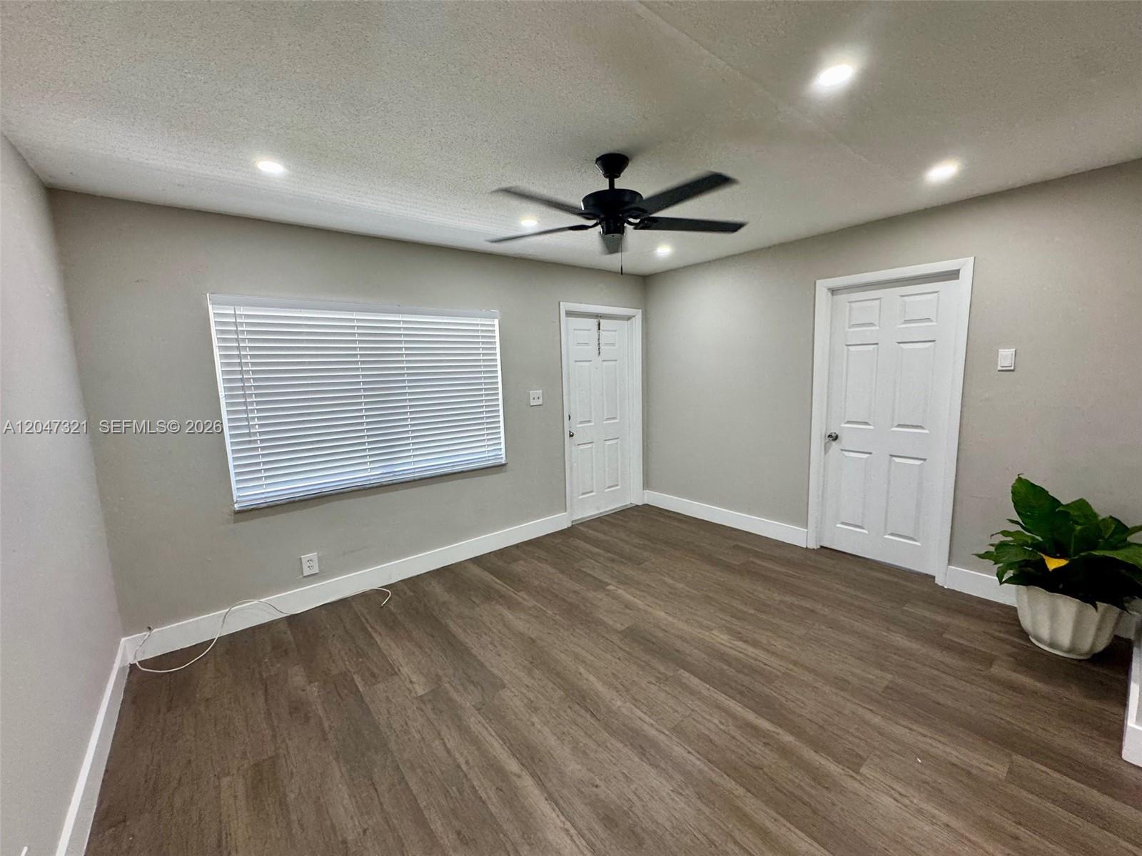 A room with light gray walls, wood-look flooring, a ceiling fan, and two white doors — 5410 NW 16th St # 1, Lauderhill FL 33313, LAUDERHILL, FL