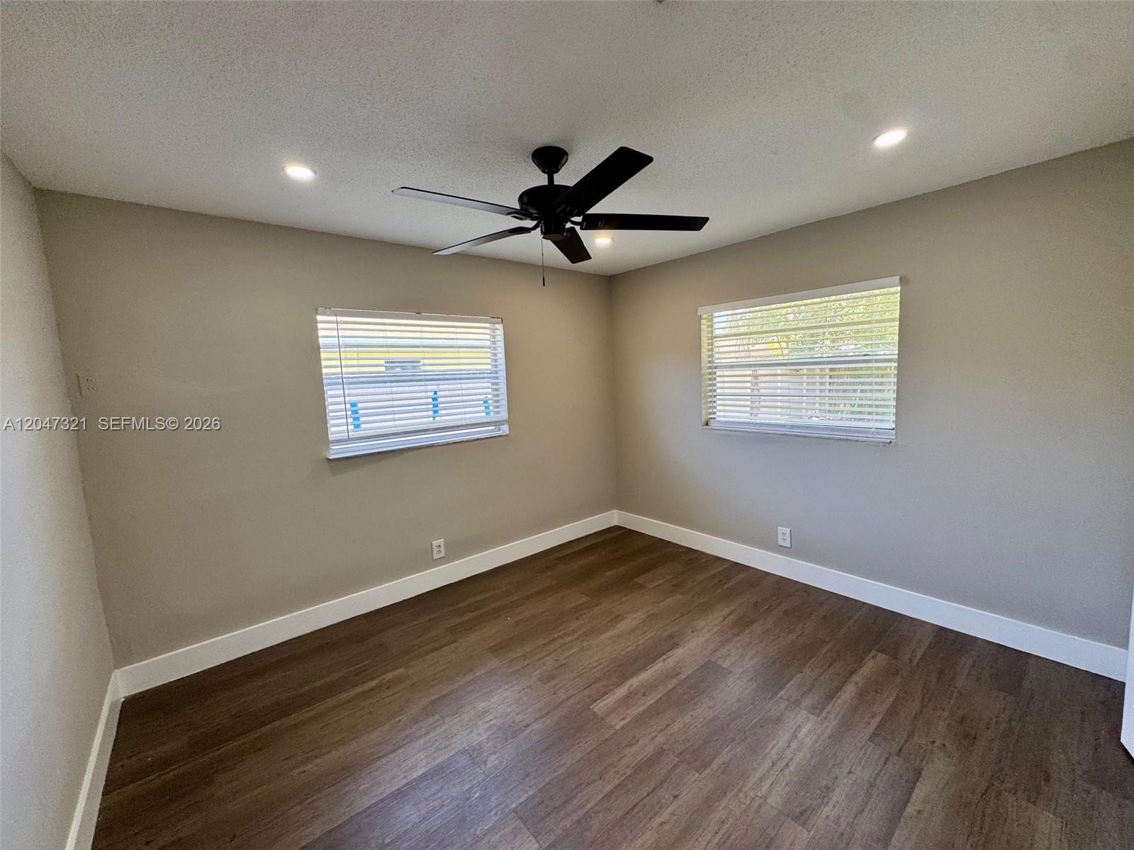 A bedroom features light gray walls, dark wood-look flooring, two windows, and a ceiling fan — 5410 NW 16th St # 1, Lauderhill FL 33313, LAUDERHILL, FL