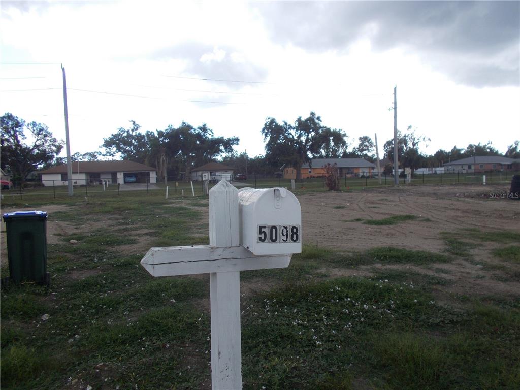A white mailbox with the number 5098 stands in front of a vacant, grassy lot — 5098 PALENA BOULEVARD, NORTH PORT, FL