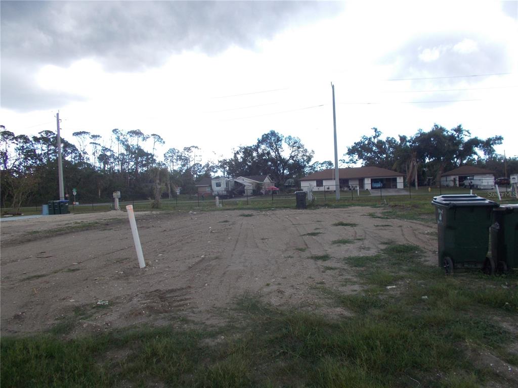 A vacant, cleared residential lot features a white utility pipe and two trash bins — 5098 PALENA BOULEVARD, NORTH PORT, FL