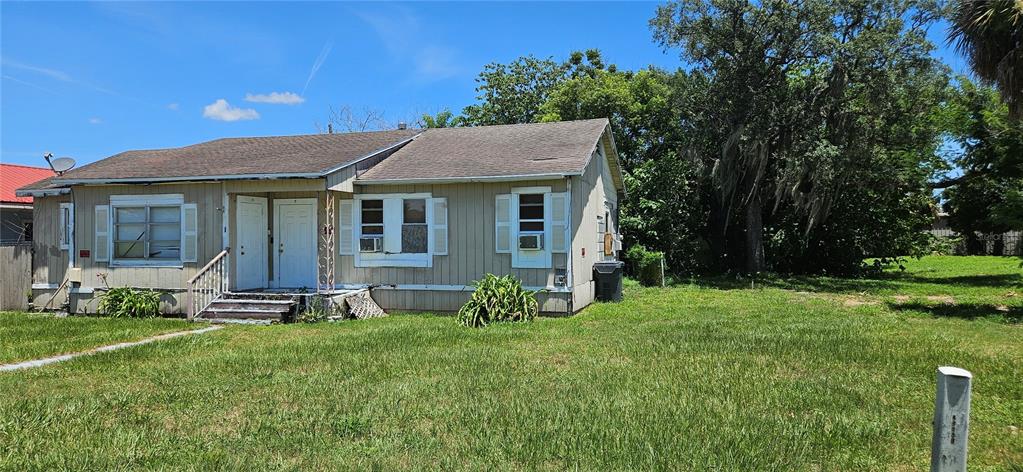A single-story house with tan vertical siding, a shingled roof, and two front entry doors — 4001 DUNDEE ROAD, WINTER HAVEN, FL