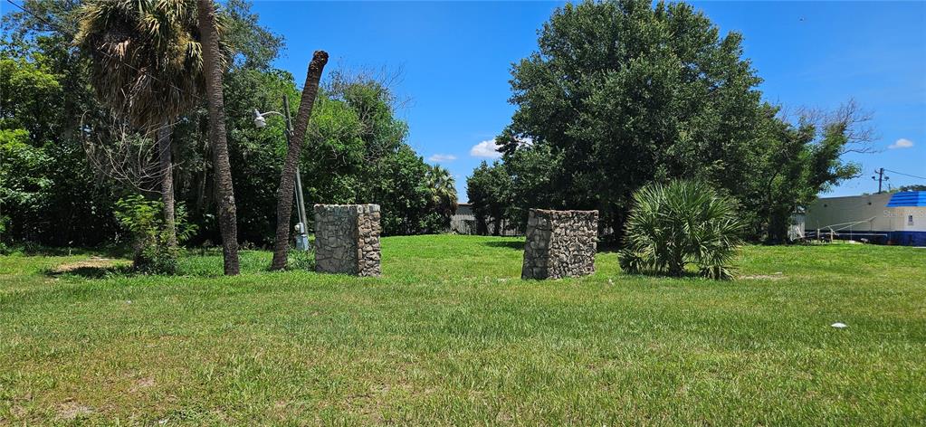 A grassy lot features two stone pillars and several trees under a clear blue sky — 4001 DUNDEE ROAD, WINTER HAVEN, FL