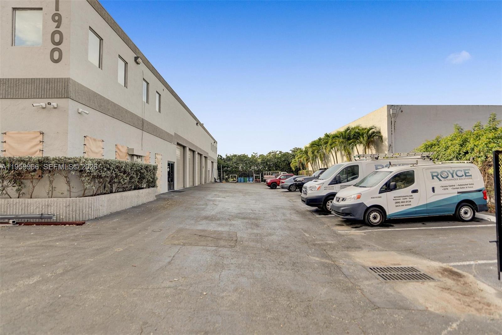 An exterior view shows a paved parking lot between two industrial warehouse buildings — 1900 NW 32nd St, Pompano Beach FL 33064, POMPANO BEACH, FL