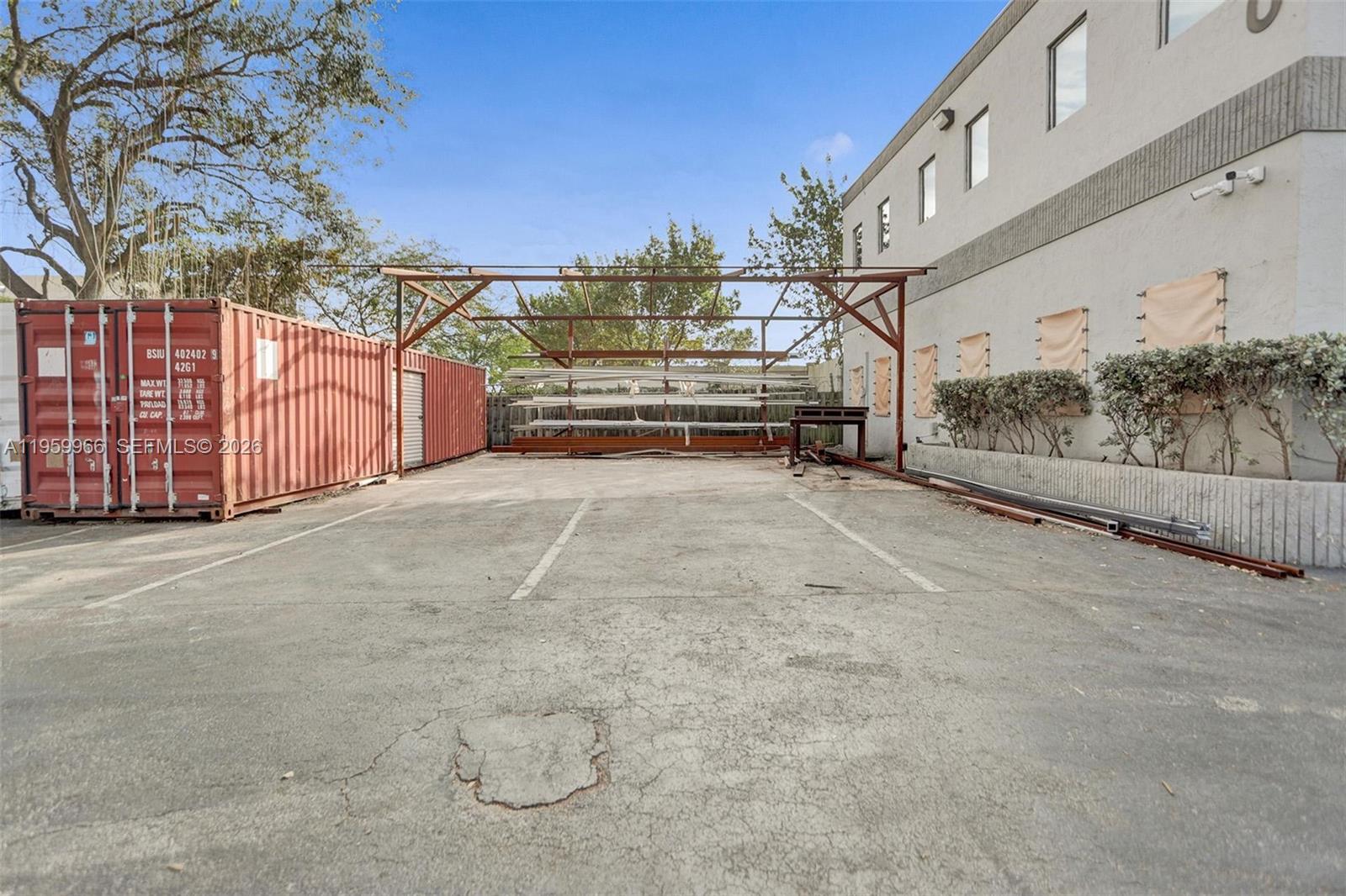 An outdoor paved area features a shipping container, a metal storage rack, and a building — 1900 NW 32nd St, Pompano Beach FL 33064, POMPANO BEACH, FL