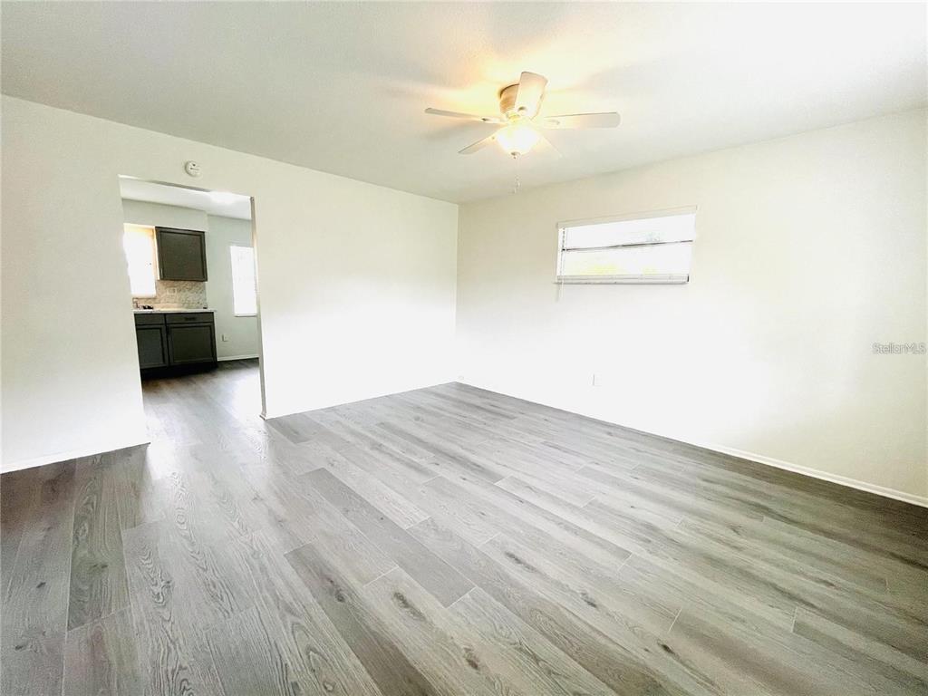 A living room with light gray wood-look flooring, white walls, and a ceiling fan — 1509 PHYLLIS STREET, LAKELAND, FL