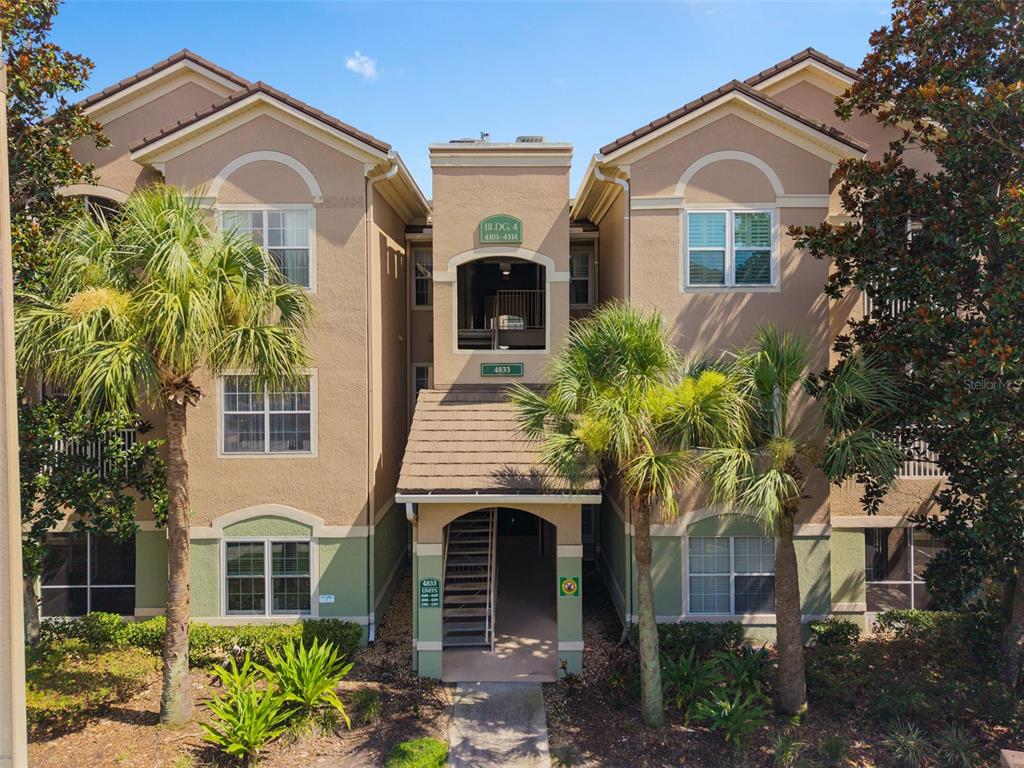 A white front door with a welcome mat and address plaque on a stucco wall — 4833 CYPRESS WOODS DRIVE UNIT 4306, ORLANDO, FL