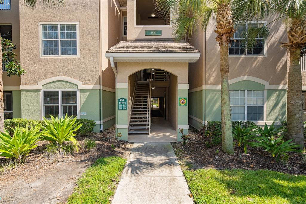 A hallway with tile flooring leads to a kitchen and dining area with wood cabinets — 4833 CYPRESS WOODS DRIVE UNIT 4306, ORLANDO, FL