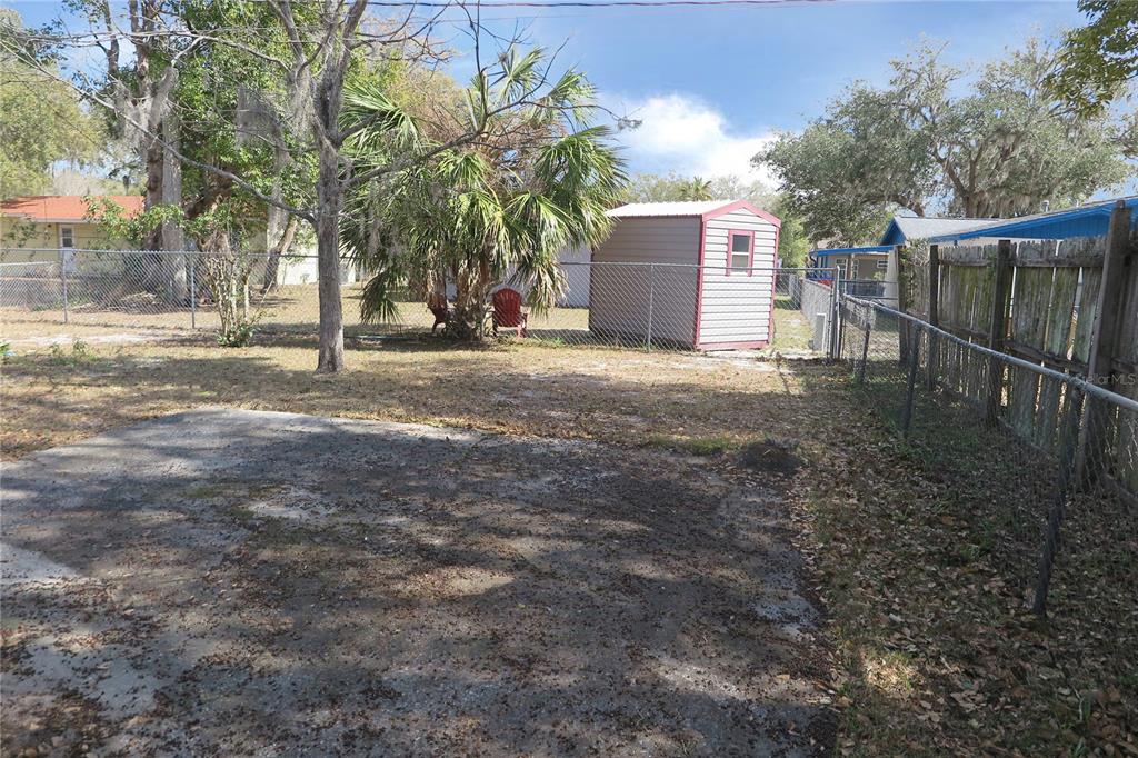 A backyard features a concrete pad, a small storage shed, and a chain-link fence — 1045 SE 19TH STREET, GAINESVILLE, FL