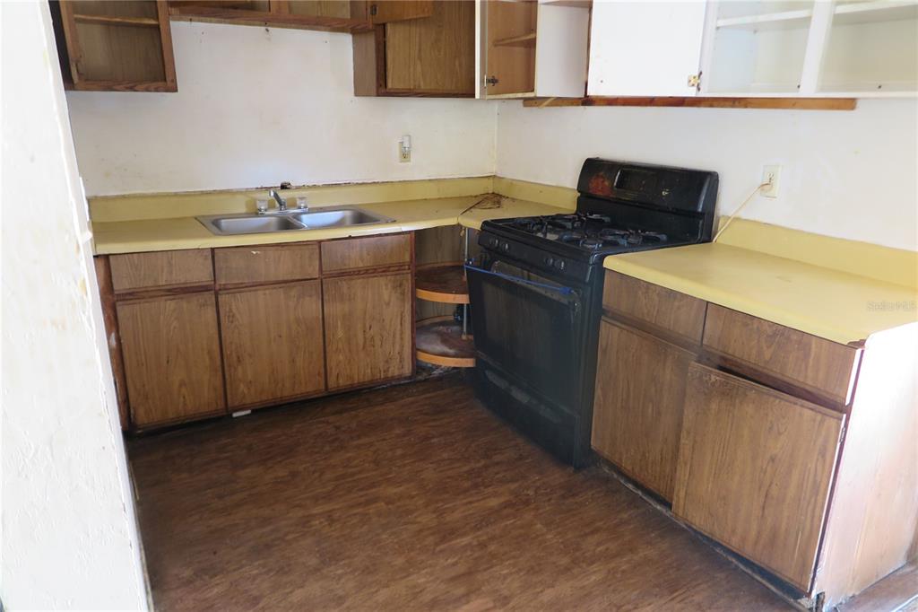 A kitchen features wood-grain cabinets, yellow laminate countertops, a black stove, and a double sink — 1045 SE 19TH STREET, GAINESVILLE, FL