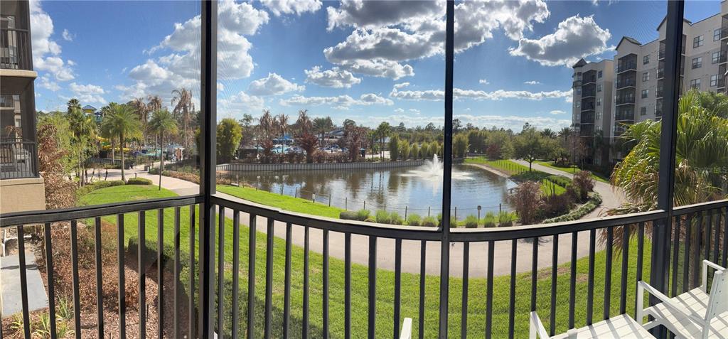 A view from a screened balcony overlooking a pond, fountain, and surrounding apartment buildings — 14501 GROVE RESORT AVENUE UNIT 3220, KISSIMMEE, FL