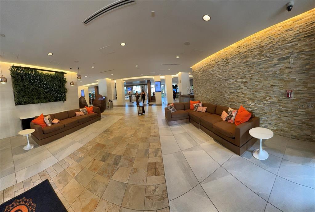 A hotel lobby features two large brown sofas, a stone accent wall, and tiled floors — 14501 GROVE RESORT AVENUE UNIT 3220, KISSIMMEE, FL