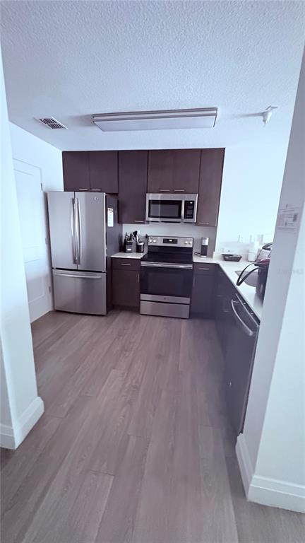 A kitchen features dark wood cabinets, stainless steel appliances, and light wood-look flooring — 14501 GROVE RESORT AVENUE UNIT 3220, KISSIMMEE, FL